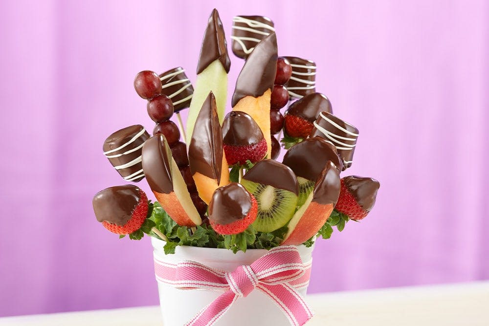 Fruits trempés dans le chocolat sur des bâtonnets à l’intérieur d’un pot de fleurs